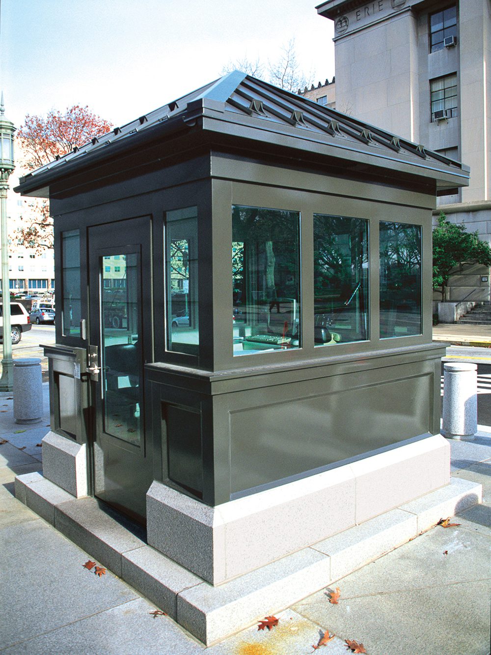 Dark gray, metal guard booth with large windows and pyramid-shaped roof